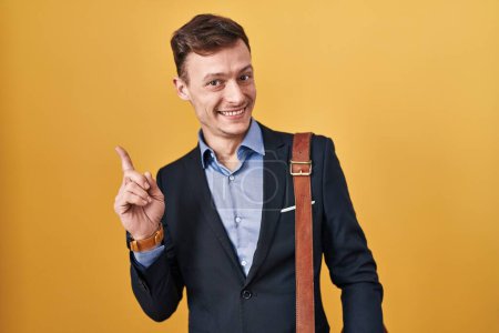 Téléchargez les photos : Homme d'affaires caucasien sur fond jaune avec un grand sourire sur le visage, pointant avec le doigt de la main vers le côté regardant la caméra. - en image libre de droit