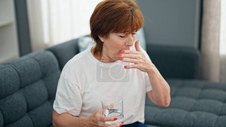 Photo for Middle age woman drinking glass of water coughing home - Royalty Free Image