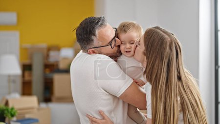 Photo for Family of mother, father and baby kissing at new home - Royalty Free Image