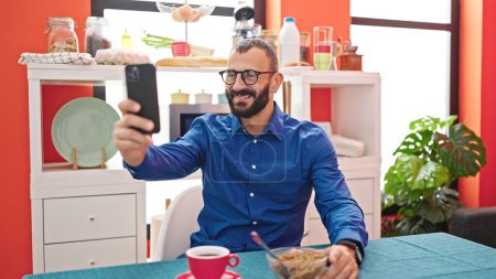 Photo for Young hispanic man doing video call having breakfast at dinning room - Royalty Free Image