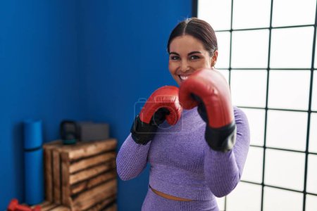Foto de Joven hermosa mujer hispana sonriendo boxeo seguro en el centro deportivo - Imagen libre de derechos