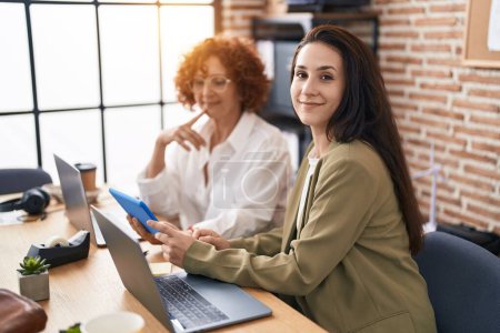 Foto de Dos mujeres trabajadoras de negocios usando laptop y touchpad trabajando en la oficina - Imagen libre de derechos