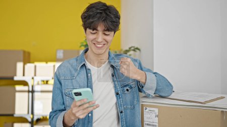 Téléchargez les photos : Jeune homme hispanique ecommerce travailleur d'affaires en utilisant un smartphone avec expression gagnante au bureau - en image libre de droit