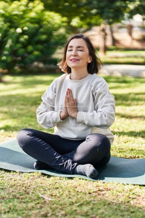 Téléchargez les photos : Femme d'âge moyen souriant entraînement confiant yoga au parc - en image libre de droit
