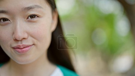 Foto de Joven mujer china sonriendo confiada de pie en el parque - Imagen libre de derechos