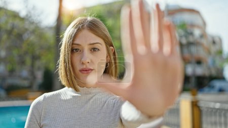 Photo for Young blonde woman doing stop gesture with hand at park - Royalty Free Image