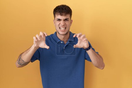 Téléchargez les photos : Young hispanic man standing over yellow background smiling funny doing claw gesture as cat, aggressive and sexy expression - en image libre de droit