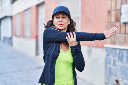 Foto de Mujer hispana de mediana edad estirando brazos al aire libre - Imagen libre de derechos