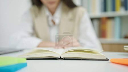 Foto de Joven hermosa mujer hispana leyendo libro pasando página siguiente en el aula universitaria - Imagen libre de derechos