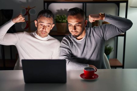 Photo for Homosexual couple using computer laptop strong person showing arm muscle, confident and proud of power - Royalty Free Image