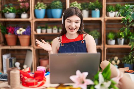 Photo for Young caucasian woman working at florist shop doing video call celebrating achievement with happy smile and winner expression with raised hand - Royalty Free Image