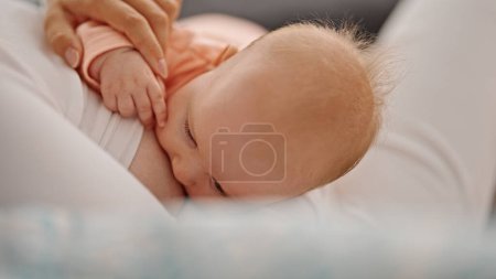 Téléchargez les photos : Mère et fille assis sur le canapé allaitement bébé à la maison - en image libre de droit