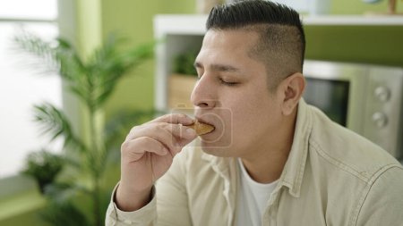 Foto de Joven hispano comiendo galletas en el comedor - Imagen libre de derechos
