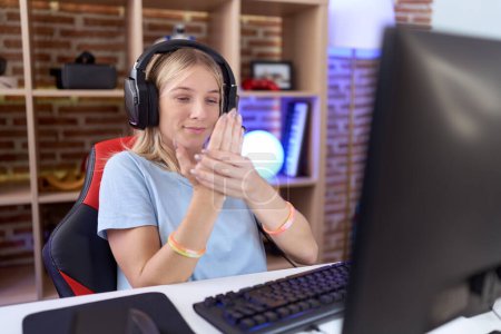 Photo for Young caucasian woman playing video games wearing headphones suffering pain on hands and fingers, arthritis inflammation - Royalty Free Image
