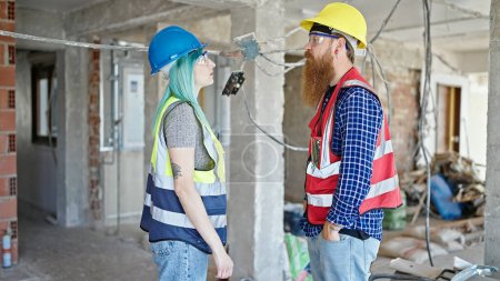 Téléchargez les photos : Constructeurs hommes et femmes debout avec une expression détendue travaillant sur le chantier de construction - en image libre de droit