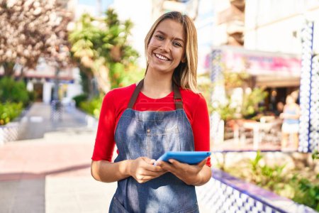 Photo for Young hispanic woman waitress smiling confident using touchpad at park - Royalty Free Image
