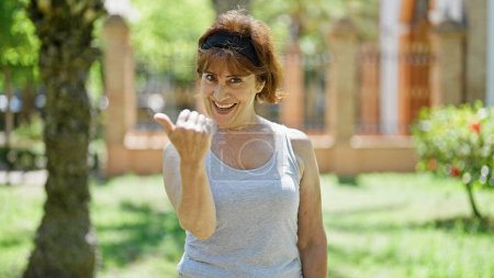Téléchargez les photos : Femme d'âge moyen souriant faire confiance geste à venir avec la main au parc - en image libre de droit