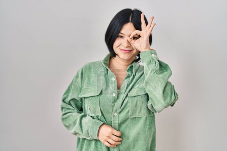 Téléchargez les photos : Jeune femme asiatique debout sur fond blanc faisant un geste correct avec la main souriante, les yeux regardant à travers les doigts avec un visage heureux. - en image libre de droit