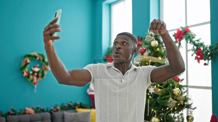 Photo for African american man celebrating christmas make selfie by smartphone holding key at home - Royalty Free Image