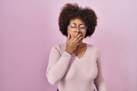 Foto de Young african american woman standing over pink background bored yawning tired covering mouth with hand. restless and sleepiness. - Imagen libre de derechos