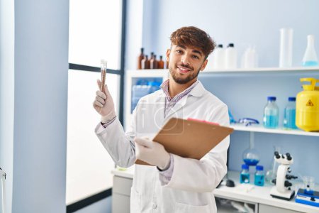 Photo for Young arab man scientist holding test tube and clipboard at laboratory - Royalty Free Image