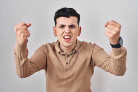 Photo for Non binary person standing over isolated background angry and mad raising fists frustrated and furious while shouting with anger. rage and aggressive concept. - Royalty Free Image