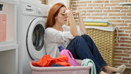 Téléchargez les photos : Jeune rousse femme laver les vêtements stressé à la buanderie - en image libre de droit