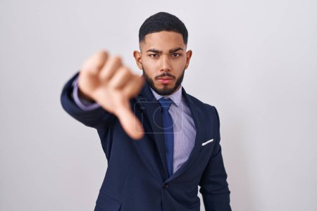 Photo for Young hispanic man wearing business suit and tie looking unhappy and angry showing rejection and negative with thumbs down gesture. bad expression. - Royalty Free Image