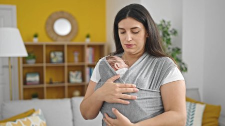 Téléchargez les photos : Mère et bébé fille portant bébé sur écharpe de maternité à la maison - en image libre de droit