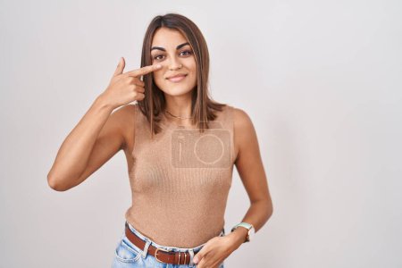 Téléchargez les photos : Jeune femme hispanique debout sur fond blanc pointant avec le doigt de la main sur le visage et le nez, souriant gai. concept de beauté - en image libre de droit