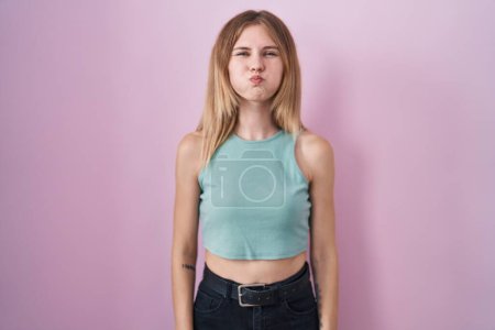 Photo for Blonde caucasian woman standing over pink background puffing cheeks with funny face. mouth inflated with air, crazy expression. - Royalty Free Image