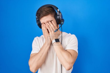 Photo for Hispanic man with beard listening to music wearing headphones rubbing eyes for fatigue and headache, sleepy and tired expression. vision problem - Royalty Free Image