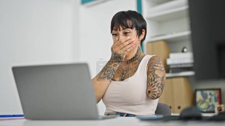 Téléchargez les photos : Femme hispanique avec amputé bras travailleur d'affaires en utilisant un ordinateur portable avec expression surprise au bureau - en image libre de droit