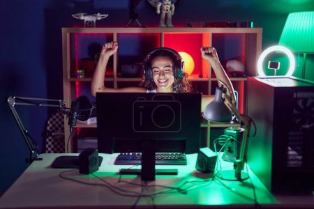 Photo for Young beautiful hispanic woman streamer playing video game with winner expression at gaming room - Royalty Free Image