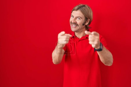 Photo for Caucasian man with mustache standing over red background pointing fingers to camera with happy and funny face. good energy and vibes. - Royalty Free Image