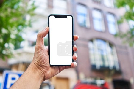 Photo for Man holding smartphone showing white blank screen at street - Royalty Free Image