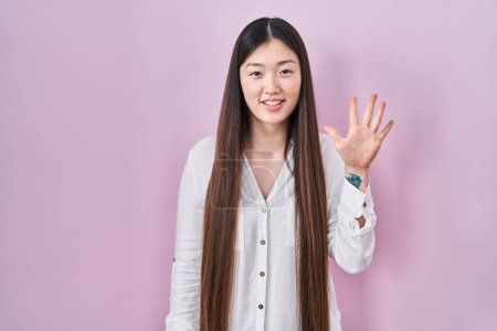 Téléchargez les photos : Chinois jeune femme debout sur fond rose montrant et pointant vers le haut avec les doigts numéro cinq tout en souriant confiant et heureux. - en image libre de droit