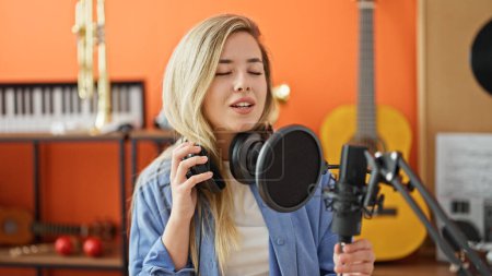 Téléchargez les photos : Jeune femme blonde musicienne souriante chanson de chant confiante au studio de musique - en image libre de droit