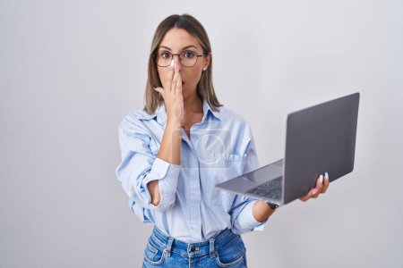 Téléchargez les photos : Jeune femme travaillant à l'aide d'un ordinateur portable peur et choqué, surprise et expression étonnante avec les mains sur le visage - en image libre de droit