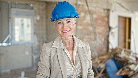 Photo for Middle age blonde woman architect smiling confident standing at construction site - Royalty Free Image