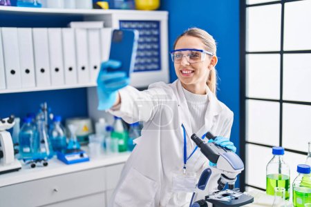 Photo for Young woman scientist smiling confident make selfie by smartphone at laboratory - Royalty Free Image