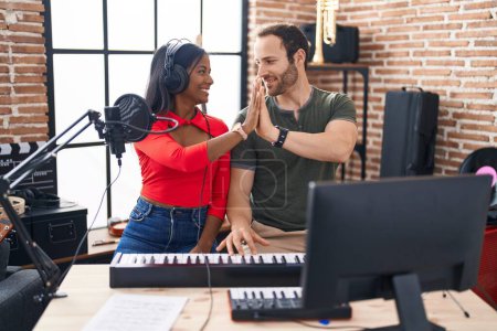 Photo for Man and woman musicians high five with hands raised up at music studio - Royalty Free Image