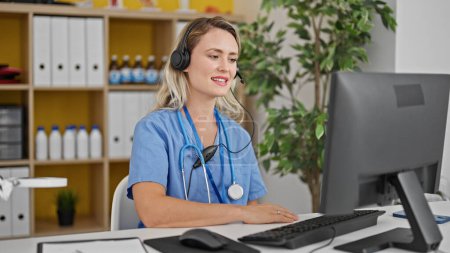 Photo for Young blonde woman doctor having video call smiling at clinic - Royalty Free Image
