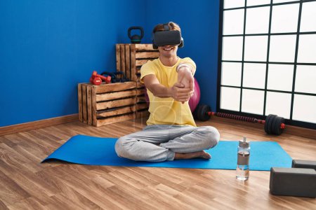 Photo for Young caucasian man using virtual reality glasses stretching at sport center - Royalty Free Image
