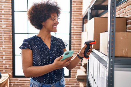 Téléchargez les photos : Africaine américaine femme commerce électronique travailleur d'affaires numérisation paquet au bureau - en image libre de droit