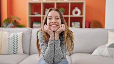 Photo for Young caucasian woman smiling confident sitting on sofa at home - Royalty Free Image