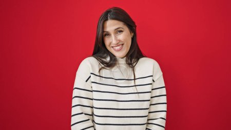 Téléchargez les photos : Jeune belle femme hispanique souriant confiant debout sur fond rouge isolé - en image libre de droit
