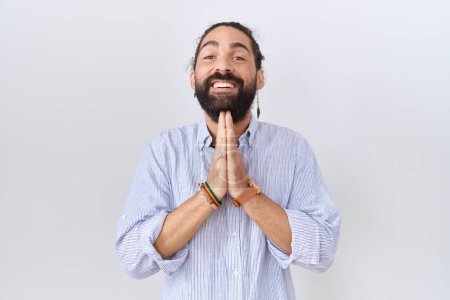 Téléchargez les photos : Homme hispanique avec barbe portant chemise décontractée priant avec les mains ensemble demandant pardon souriant confiant. - en image libre de droit
