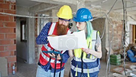 Photo for Man and woman builders using touchpad reading house project at construction site - Royalty Free Image