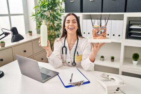 Photo for Hispanic doctor woman holding model of human anatomical skin and hair smiling and laughing hard out loud because funny crazy joke. - Royalty Free Image